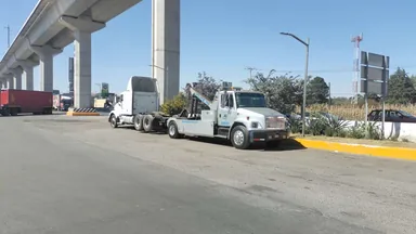Grúa de arrastre remolcando un vehículo pesado bajo un paso a desnivel